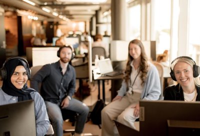 Fire personer med hodetelefoner gir rådgivning på et kontor.