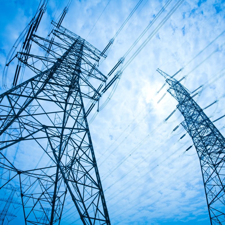To høye elektriske kraftledninger mot en blå himmel med skyer.
