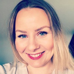 Kvinne med langt blondt hår smiler mot kameraet.
